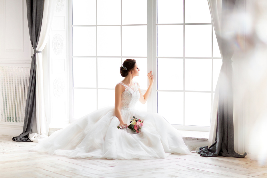 Beautiful brunette woman with bouquet posing in a wedding dress